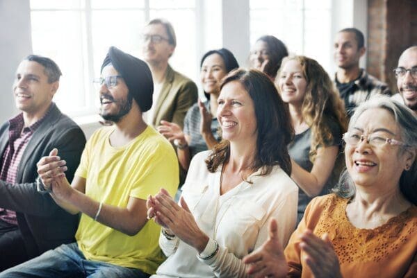 Diverse audience in a meeting smiling and clapping