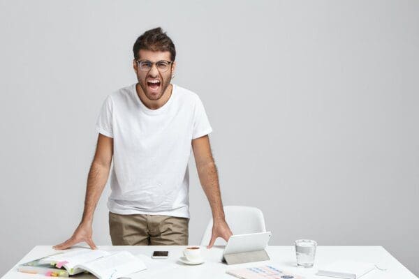 Angry male employee shouting at work desk