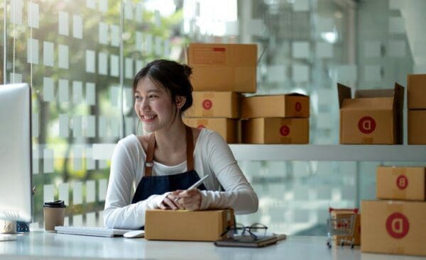  Small business entrepreneur writing address on cardboard box at work