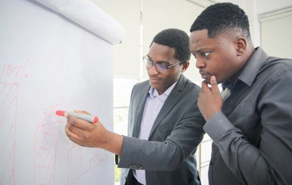 Businessman learning from his coach writing on a whiteboard