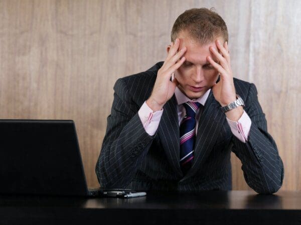 Businessman head in hands Businessman head in hands in office after receiving another generic email that says 'I hope you are well'
