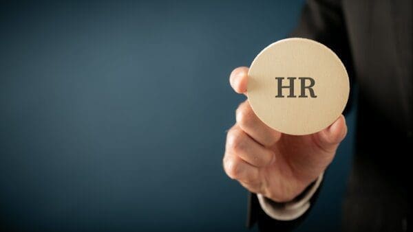 HR Businessman holding a wooden cut circle with HR letters to represent the Human Resource job function