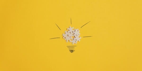 Lightbulb image created from puzzle pieces on yellow background 