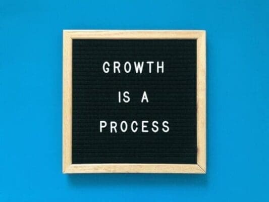 Growth is a process quote on a felt board against a blue background