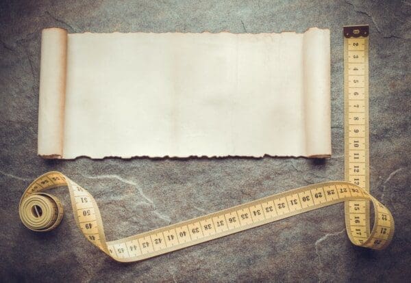 Measuring tape on a table with a scroll of white paper