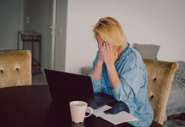 Woman at home desk with head in hands