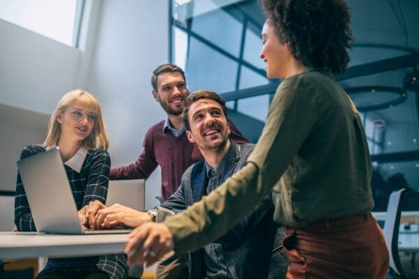 Three business employees smiling at their female leader around a desk