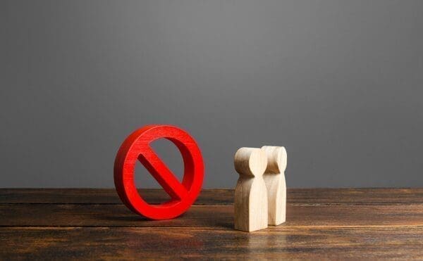 Two wooden figures in front of a red stop sign