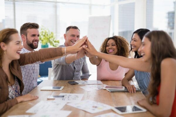 Team of executives high-fiving over a table