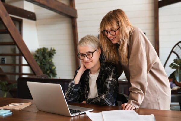 Female employee at her desk with work coach standing over her