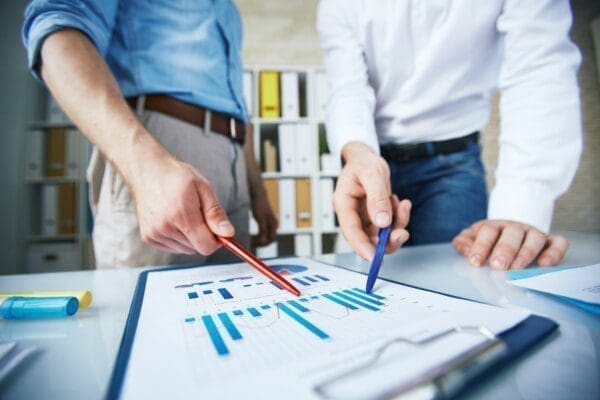 Close up of businessmen pointing at statistics on a clipboard