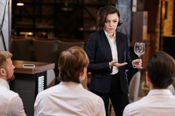 Restaurant manager Confident restaurant manager briefing employees on menu while holding a wine glass