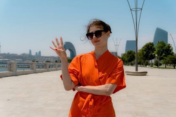 Four fingers woman in orange top holding up four fingers