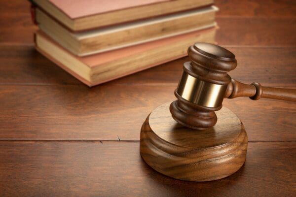 Brown wooden gavel on the surface with a pile of books