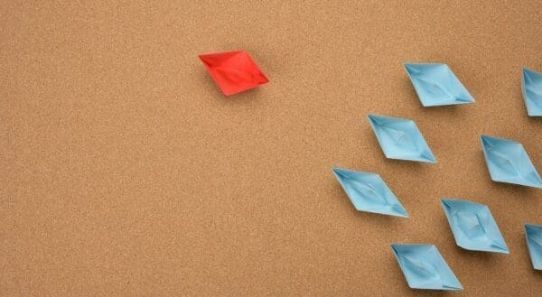 red paper boat leading blue boats