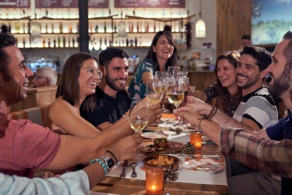 Smiling people gathering in bar and drinking alcohol