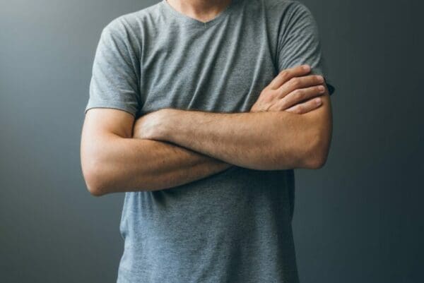 Man in a grey shirt with arms crossed showing body language