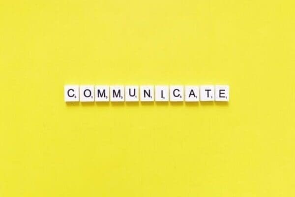 Communicate spelled with white cubes on a yellow background