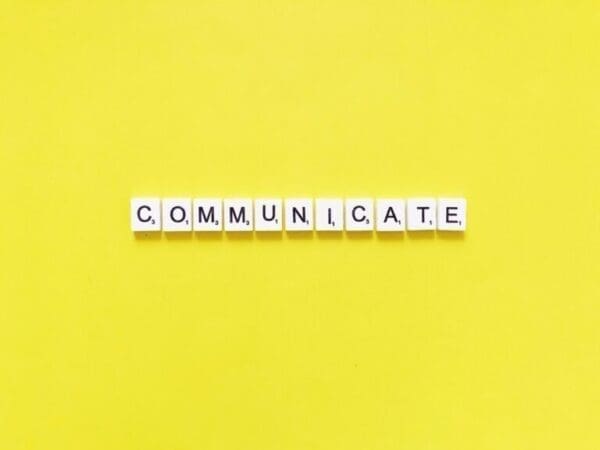 Communicate Communicate spelled with white cubes on yellow background