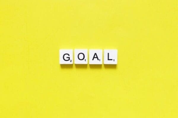 Goal spelt with white word scramble cubes on yellow background