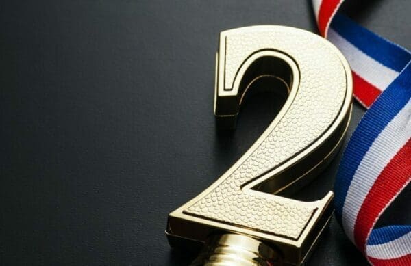 Number Two Gold number two next to blue, red and white award ribbon on grey surface
