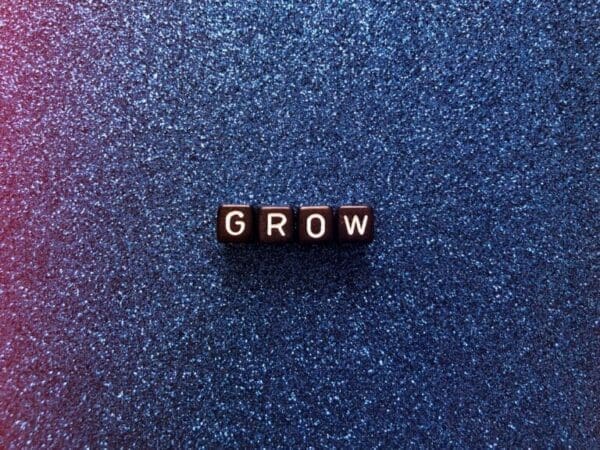 grow Grow spelled with black cubes on blue sparkly background