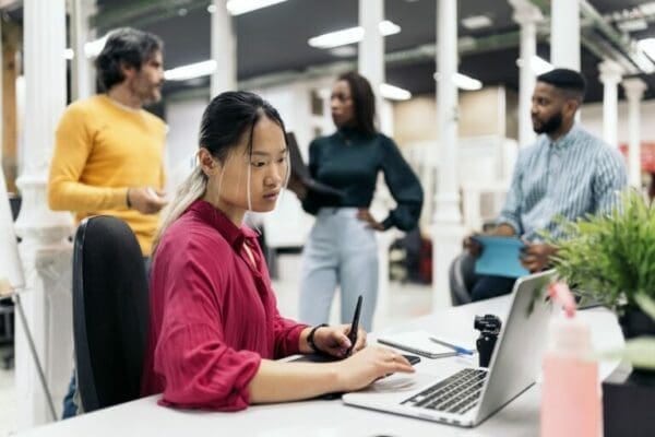 Female Asian office worker on a laptop at her desk is researching how to work remotely