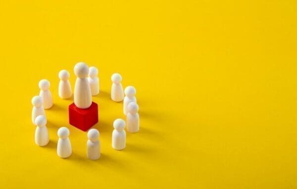 leader Strategic leader wooden figure on a red podium surrounded by followers on yellow background