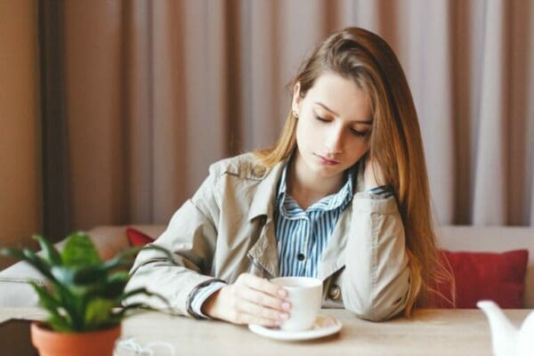 sad worker Sad female remote worker behind a table holding a teacup