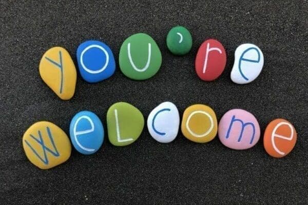 you're welcome You’re welcome spelled with multi colored stones on dark sand