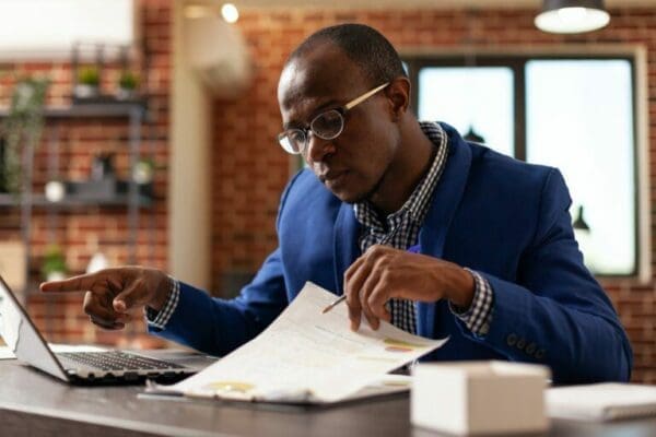 Business man analyzing papers on clipboard to plan leadership strategy with laptop