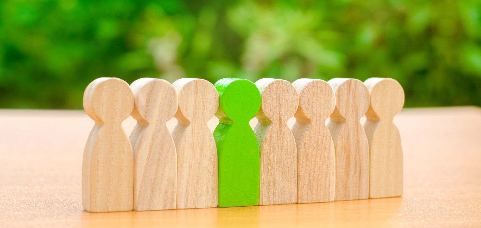 people Wooden figures of people with one single green figure