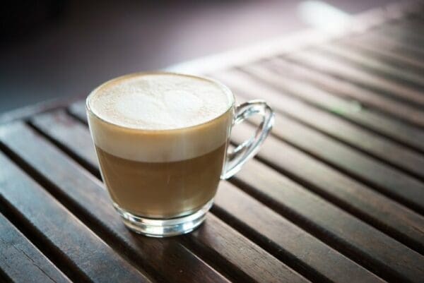 Close up of cofee mug with heart shaped milk pattern on wooden table for tips to influence people