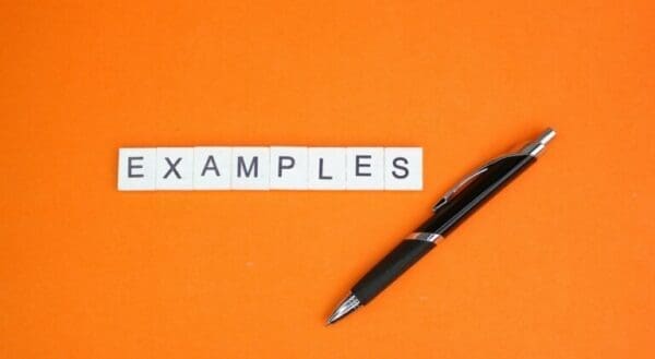Examples Examples spelled with white cubes on orange surface next to black pen time management