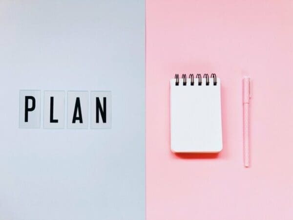 Plan Plan next to a blank notepad and pink pen