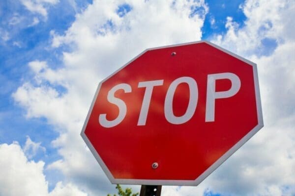 Red stop sign with blue sky and clouds in the background