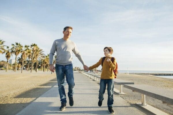 Father and son walking Father and son walking on beach promenade for life lessons