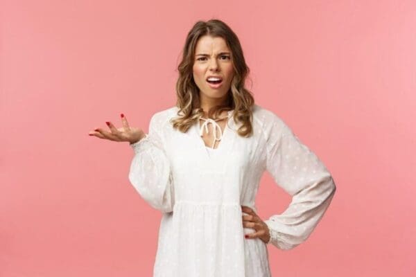 Woman showing body language to ask Whats your problem with pink background