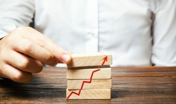 Hand holding wooden bricks with red performance upward arrow