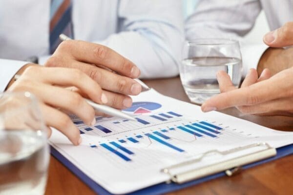 hands with pens reviewing data on a desk about Range Reviews and Resets