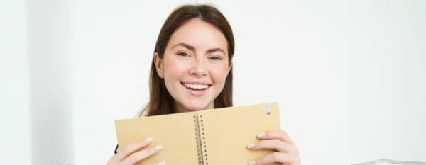 Top view of happy woman smiling while showing the back of her daily planner