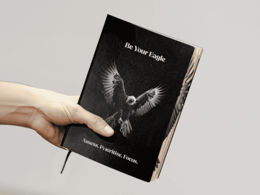 Black and white planner with an eagle on the front being held by a hand