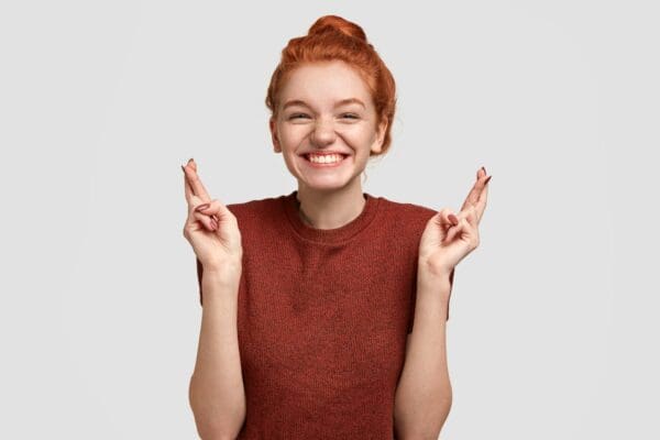 Female presenter giving luck gesture with fingers while smiling