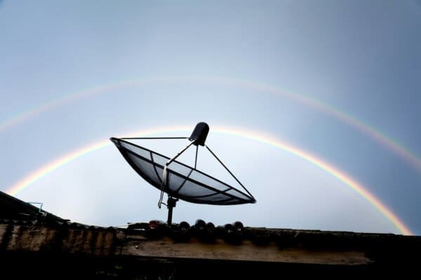 satellite dish radar on the roof against rainbow sky