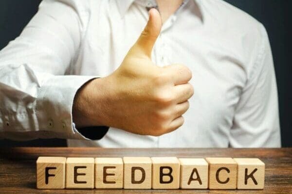 Hand giving thumbs up above blocks spelling feedback