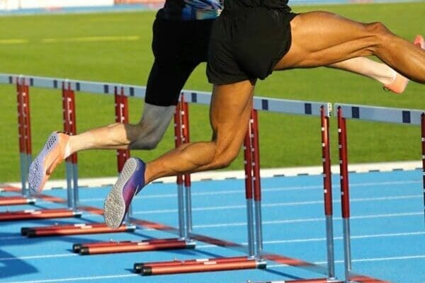 Two people jumping over a hurdle