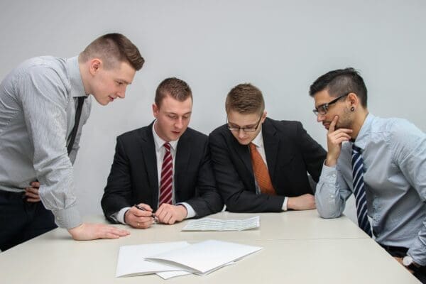 4 Men sat around a table reading Competition GSCOP law