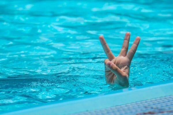 3 fingers held above water surface in a pool