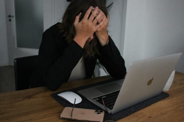 a business woman who is stressed and frustrated over chasing people covering her face at her laptop