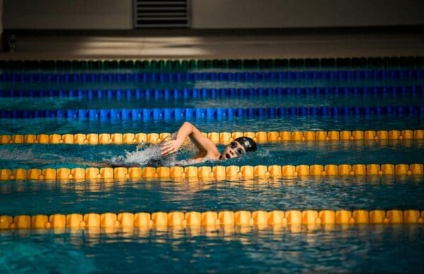 Person swimming between yellow and blue lane dividers taking a breath mid-stroke - the swimmers I was comparing myself to